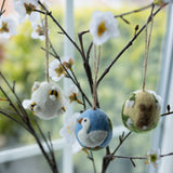 Decorative ornaments shaped like a swan, owl, and fish hanging on branches with flowers.