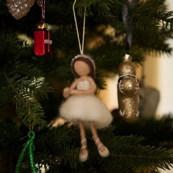 White hand-felted ballerina ornament hanging on a Christmas tree. Crafted from soft, high-quality wool, it features intricate details and adds elegance to holiday decor.