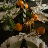 Close-up of cream white Bow placemat on a Christmas table, highlighting the large voluminous bows, scalloped edges, and the intricate details of the placemats set against a festive table setting with holiday decor.