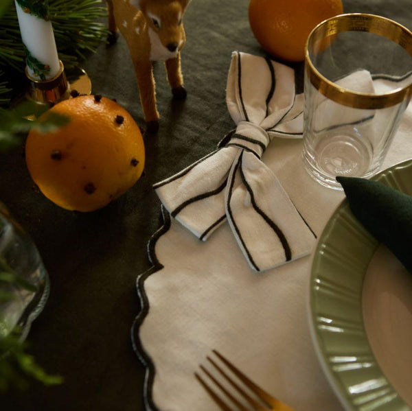 Close-up of a cream white Bow placemat, highlighting the large, voluminous bow and the beautifully scalloped edges that enhance the placemat's elegant design.