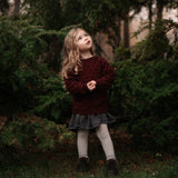 Young girl standing in a forest with trees in the background