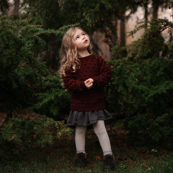 Young girl standing in a forest with trees in the background