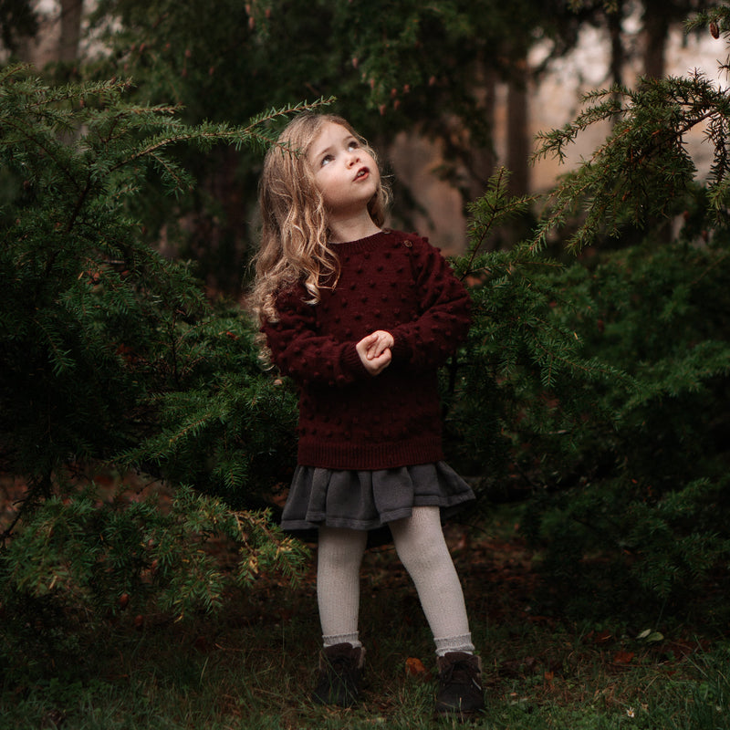 Young girl standing in a forest with trees in the background