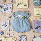 Collection of baby clothing and accessories with animal patterns on a beige background