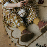 a little girl sitting on a felted gingerbread tree rug for christmas