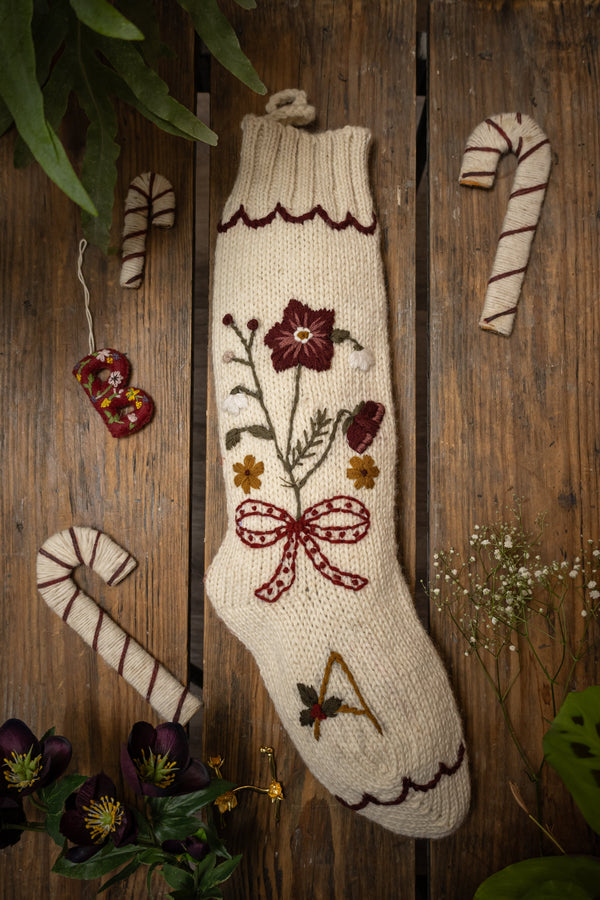 Decorative knitted stocking with floral embroidery on a wooden background