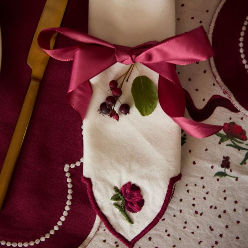 Close-up of Christmas Hellebore napkin on a table setting, showcasing the intricate embroidery of hellebores on the pristine white fabric and the elegant presentation in a festive dining arrangement.