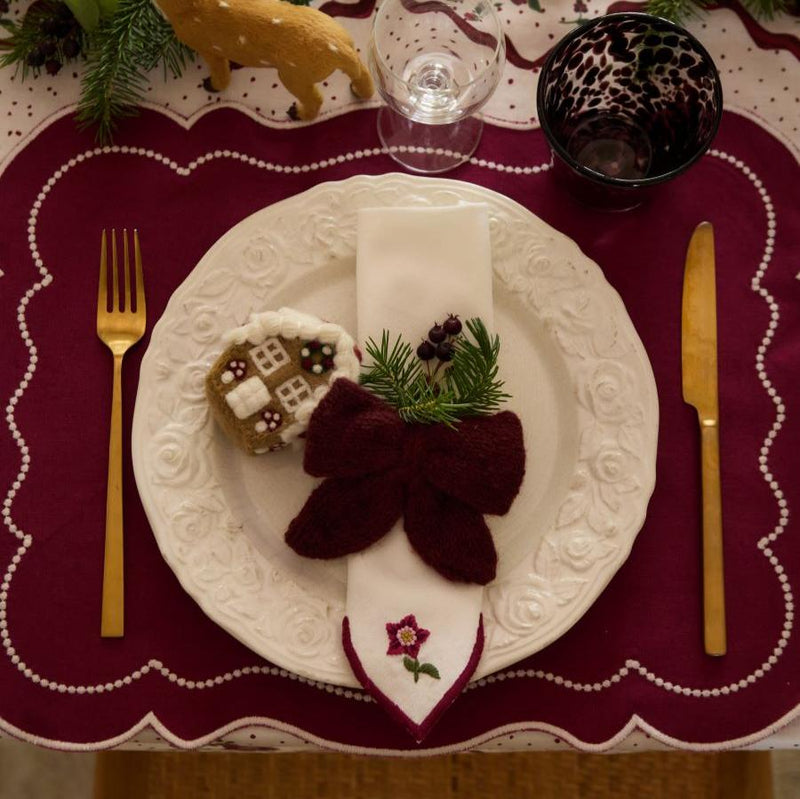 Little Bow Ornament in Grape color used as a napkin ring, enhancing holiday table settings with a beautiful and elegant detail.