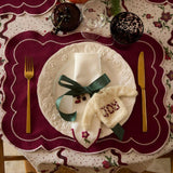 Sweater ornament with 'JOY' embroidery displayed on a festive napkin, adding a cheerful touch to the holiday table decor.