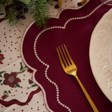 Close-up of the grape-colored embroidered dot placemat, highlighting the intricate embroidery, delicate dots, and scalloped edges.