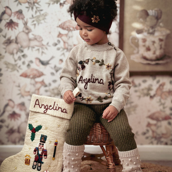 Young girl holding or displaying a personalized Nutcracker stocking with embroidered holiday motifs