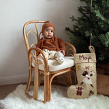 a little baby sitting next to a christmas tree with a personalized felted odette stocking