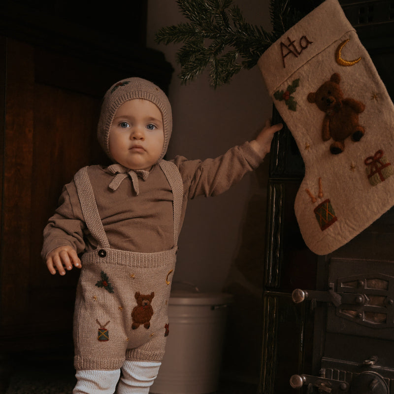 little boy in knitted suspender shorts and bonnet