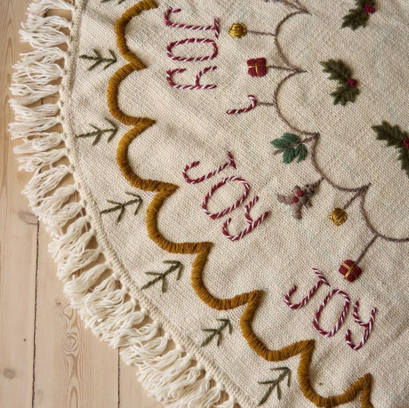 Close-up of hand-embroidered details on Joy Heirloom Tree Rug, showcasing the intricate craftsmanship and quality of the knitted Christmas tree skirt.