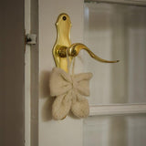 Little Bow Ornament in Cream White color hanging on a door handle, providing a gorgeous and versatile touch to home decor.