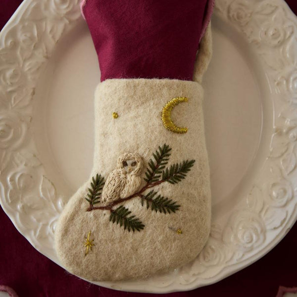 Mini Stocking with hand-embroidered owl motif displayed on a plate, with a napkin inside. The charming design showcases intricate embroidery and adds a festive touch to table settings.