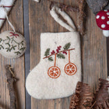 Mini Stocking with hand-embroidered orange motif, displayed in a festive Christmas setting. Surrounded by holiday decorations, the stocking's detailed embroidery and seasonal charm are highlighted.