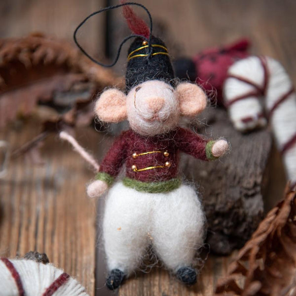 Handcrafted mouse nutcracker ornament on a wooden surface in a Christmas setting, surrounded by festive decorations, capturing the charm and traditional craftsmanship of the holiday season.