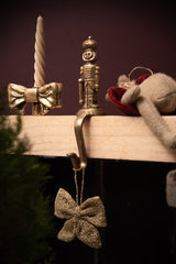 mini knitted bow gold ornament hanging on a brass nutcracker hook