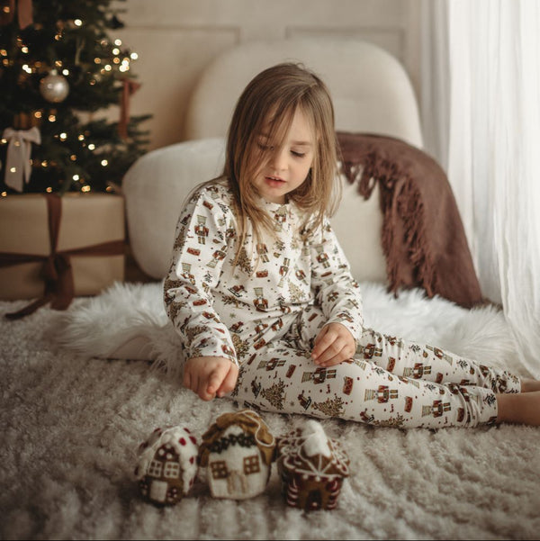 Child in pajamas sitting on a bed with Christmas decorations in the background