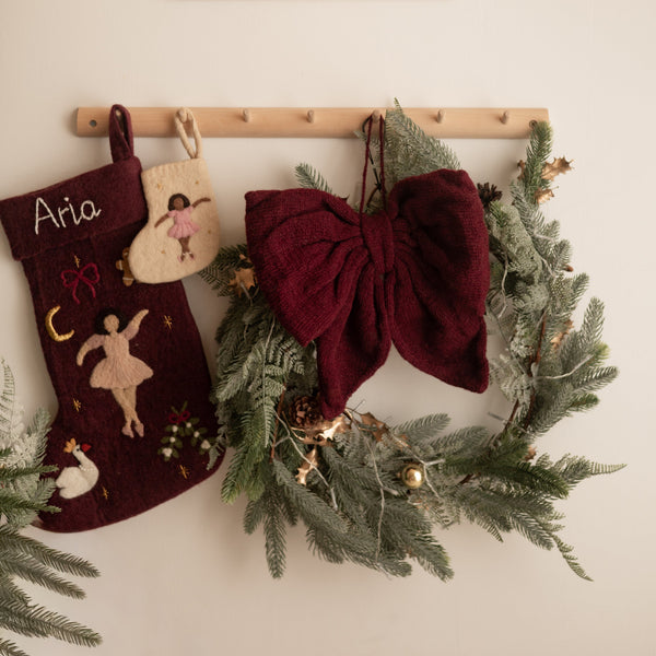 Decorative Christmas stockings and wreath hanging on a wall with a framed picture above.