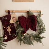 Decorative stockings and wreath hanging on a wall with a framed picture above.