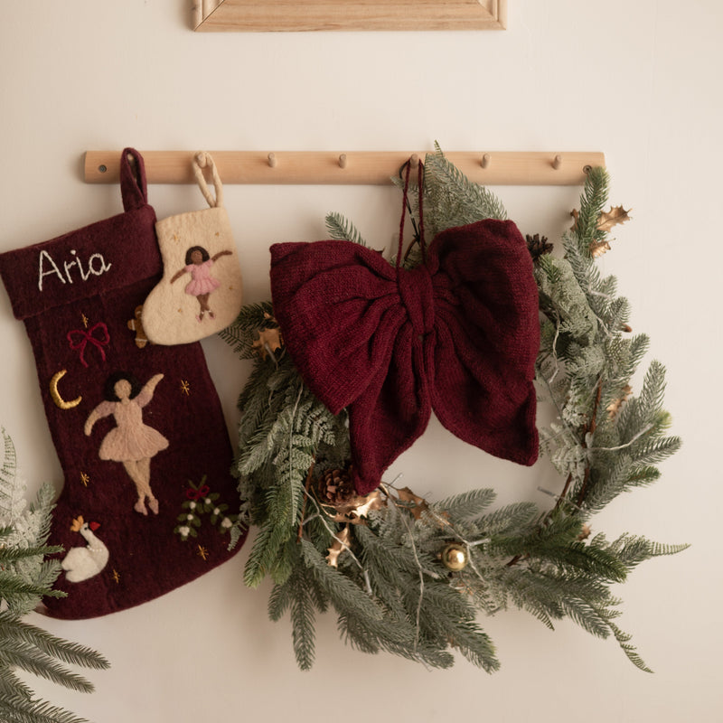 Decorative stockings and wreath hanging on a wall with a framed picture above.