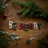 Personalized Christmas Garland surrounded by various types of green foliage and Christmas tree branches, highlighting its customizable letters and festive charm.







