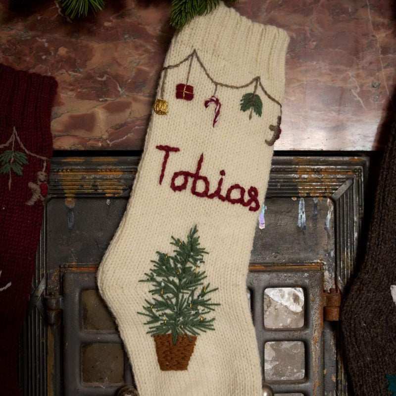 Close-up of hand-embroidered basket with Christmas tree, garland with festive elements, and custom name on Personalized Garland Stocking in Cream White color.