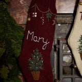 Close-up of hand-embroidered basket with Christmas tree, garland with festive elements, and custom name on Personalized Garland Stocking in Dark Grape color.