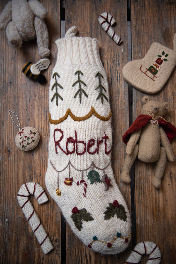 white personalized knitted stocking with hand embroidered holiday motifs