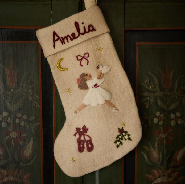 Handcrafted cream white stocking featuring personalized embroidered Odette, resting on a wooden surface, highlighting its detailed design and 100% wool material.