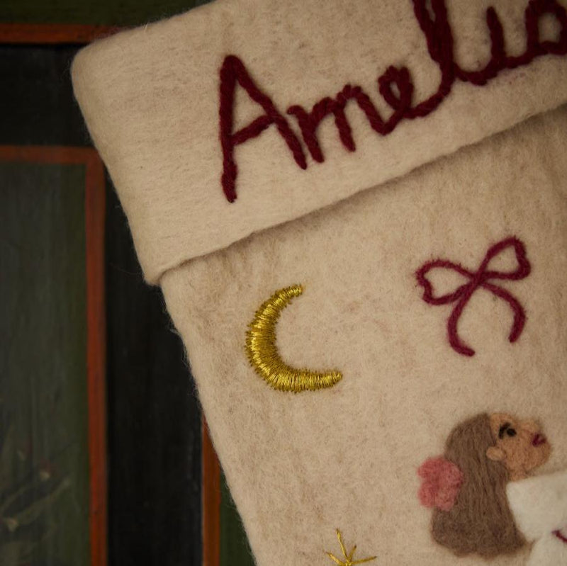 Close-up of personalized embroidered Odette on cream white holiday stocking, showcasing meticulous handcrafting and punch needle details.