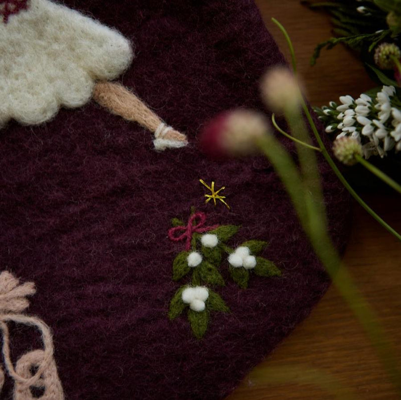 Close-up view of the embroidered holiday motifs on the personalized dark grape stocking, showcasing the fine details and craftsmanship.