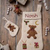 personalized felted teddy stocking on a flatlay with matching teddy ornament and a mini stocking