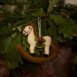 Hand-felted rocking horse ornament hanging on a Christmas tree, adding a touch of nostalgic charm and whimsy to the holiday decor.