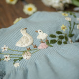 Embroidered fabric with birds and flowers on a light blue background