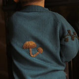 little boy wearing petroleum knitted and embroidered bugs life cardigan