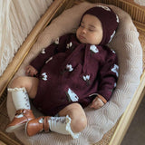 baby sleeping in knitted and embroidered hellebores romper and bonnet