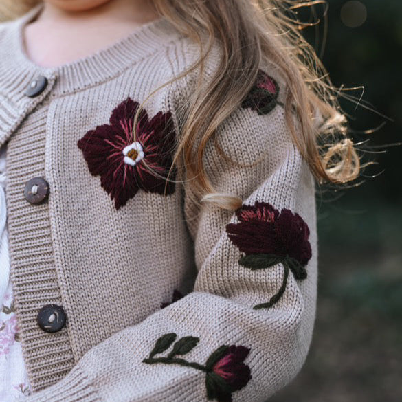 a girl wearing knitted and embroidered hellebores cardigan