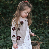 a girl wearing knitted and embroidered hellebores cardigan