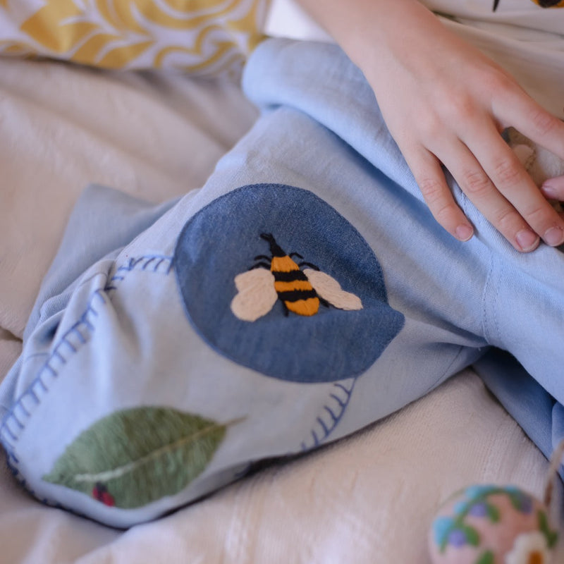 close up of the blue pants with embroidered bee and a leaf