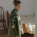 girl in a room wearing green sewn dress