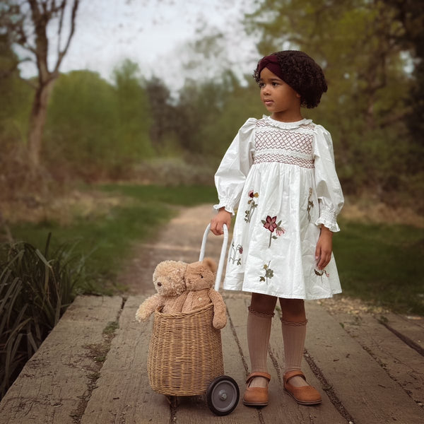 girl in nature in white dress with flower embroidery