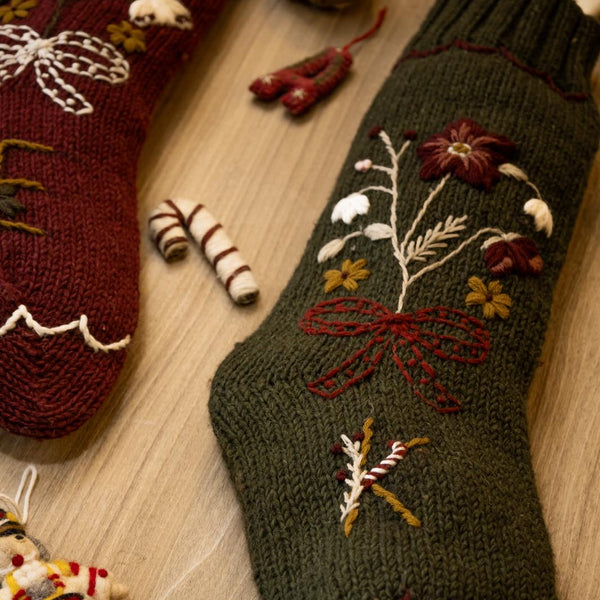 Knitted Christmas stockings with floral patterns on a wooden surface.