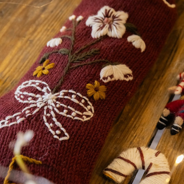 Decorative red sock with floral and bow design on a wooden surface