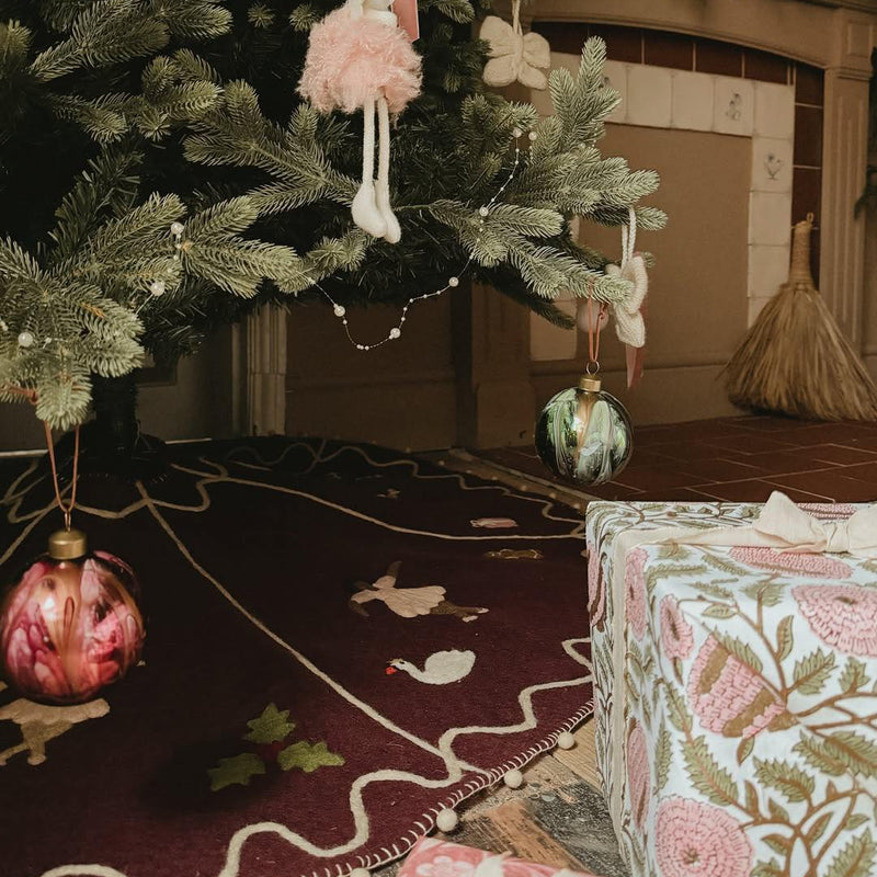 Decorated Christmas tree with ornaments and presents in a cozy living room.