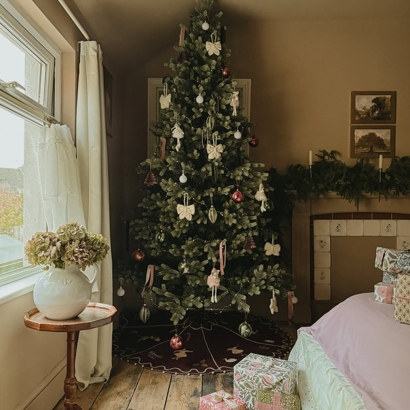 Decorated Christmas tree in a room with presents and a side table.