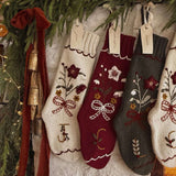 Decorative Christmas stockings with floral patterns hanging on a stone wall.