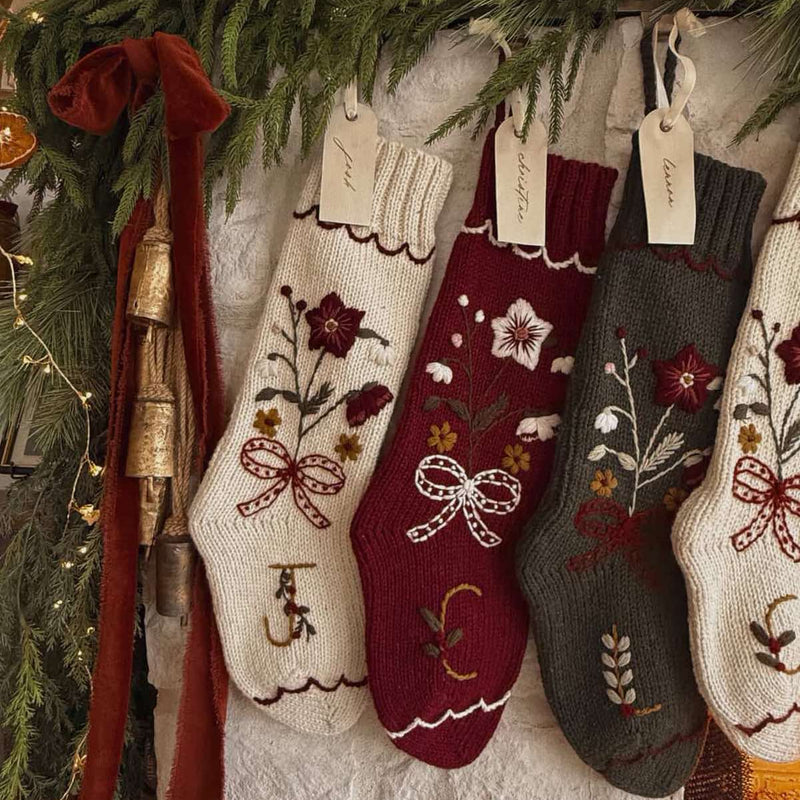 Decorative Christmas stockings with floral patterns hanging on a stone wall.